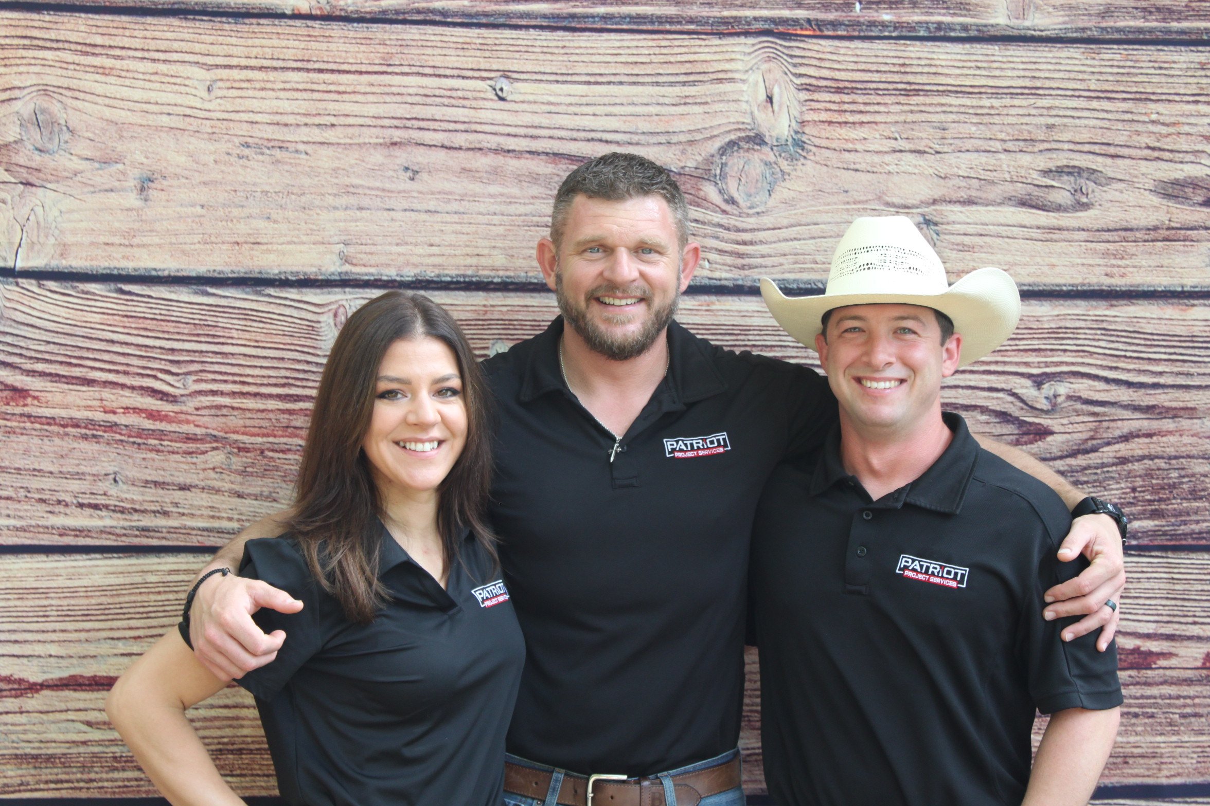 3 team members smiling in black work polos